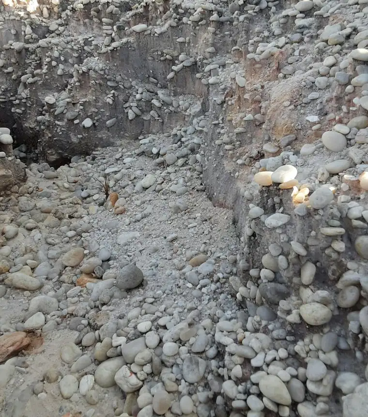 Excavated trench beside a foundation showing the soil profile
